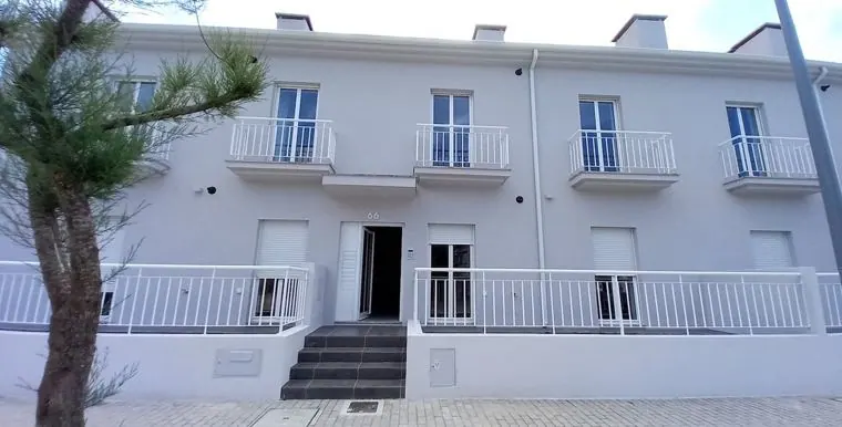 Bloco de habitação com fachada branca, varandas e escadas de acesso