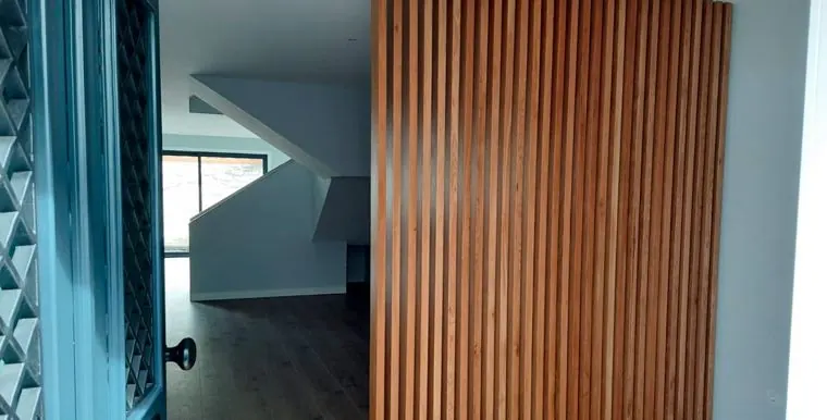 Revestimento em ripado de madeira ao lado de uma porta envidraçada
