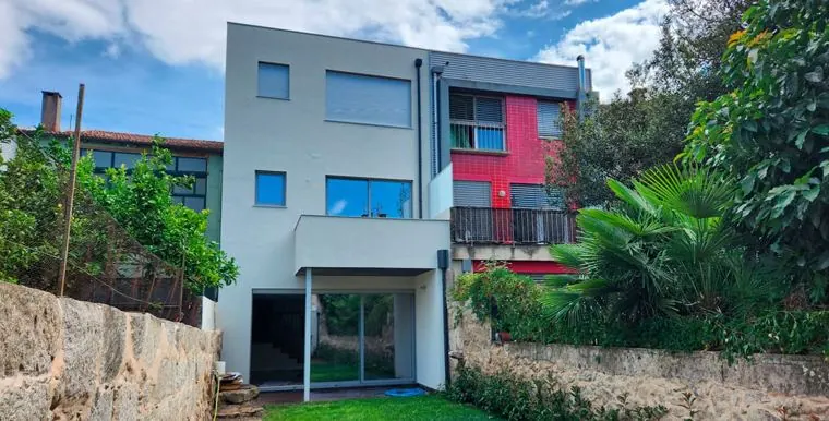 Moradia contemporânea de três pisos com jardim e muro de granito