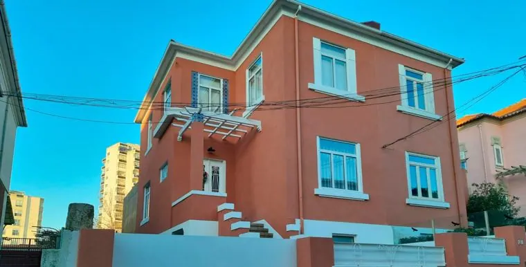Fachada coral de moradia reabilitada com caixilharia azul-claro