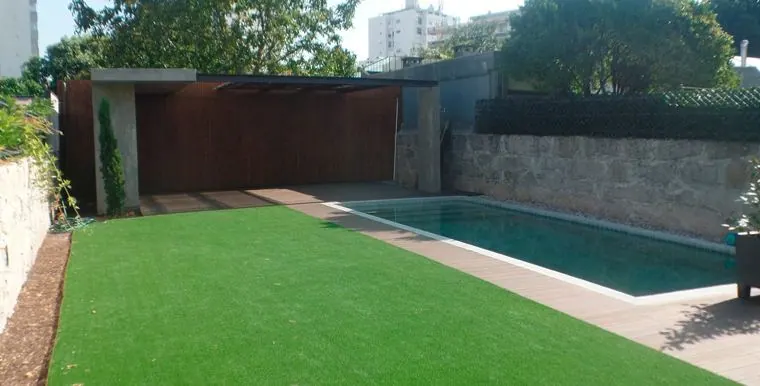Piscina e relvado com muro de granito e anexo em madeira